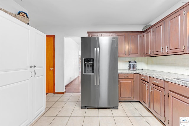 kitchen with light tile patterned floors, tasteful backsplash, and stainless steel refrigerator with ice dispenser