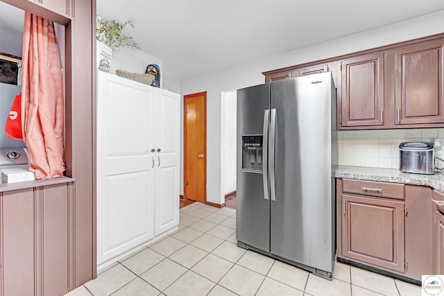 kitchen with decorative backsplash, light tile patterned flooring, light stone countertops, and stainless steel fridge