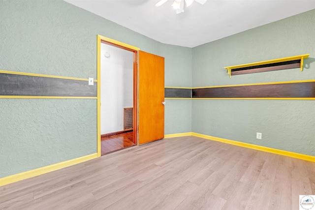 empty room featuring visible vents, a ceiling fan, a textured wall, and wood finished floors