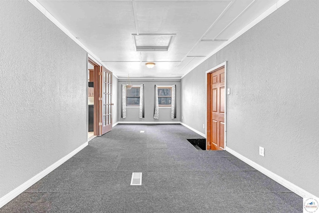 unfurnished room with baseboards, carpet, a textured wall, and visible vents