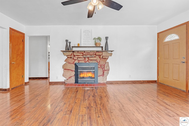 unfurnished living room with baseboards, ceiling fan, wood finished floors, and a fireplace