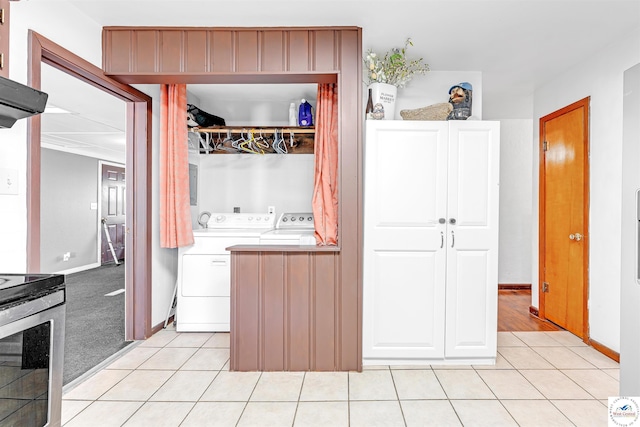 laundry area with light tile patterned floors, baseboards, washer and clothes dryer, and laundry area