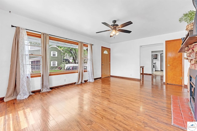 unfurnished living room with ceiling fan, baseboards, light wood finished floors, and a fireplace