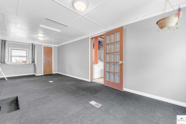 spare room with attic access, visible vents, baseboards, washer / dryer, and dark carpet