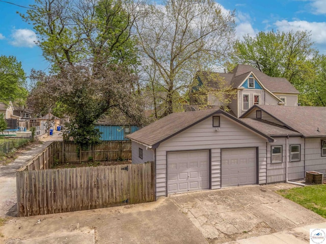 garage featuring fence and concrete driveway
