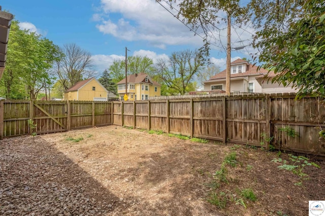 view of yard featuring a fenced backyard, a gate, and a residential view
