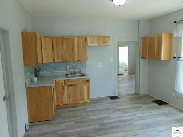 311 N Water St, Clinton, MO 64735 - kitchen with light wood-style flooring, a sink, visible vents, light countertops, and backsplash