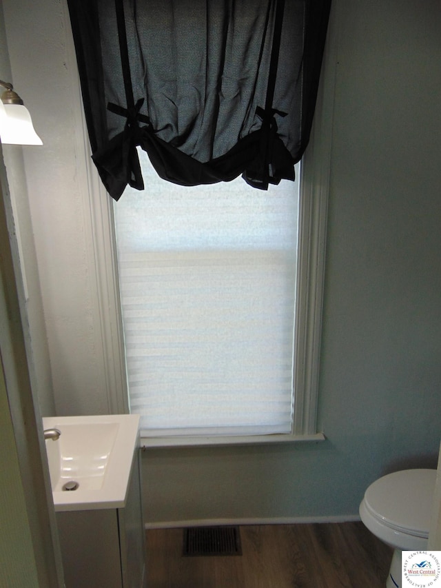 311 N Water St, Clinton, MO 64735 - half bath with wood finished floors, toilet, vanity, baseboards, and visible vents