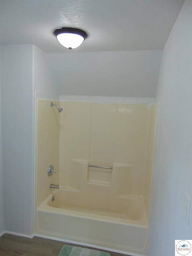 311 N Water St, Clinton, MO 64735 - full bath featuring a textured ceiling, shower / tub combination, wood finished floors, and baseboards
