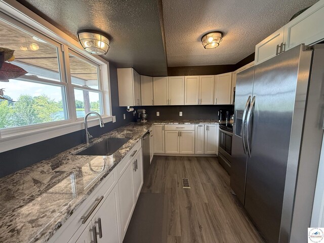 225 Crescent Dr, Lincoln, MO 65338 - kitchen featuring appliances with stainless steel finishes, dark wood finished floors, white cabinets, a textured ceiling, and light stone counters