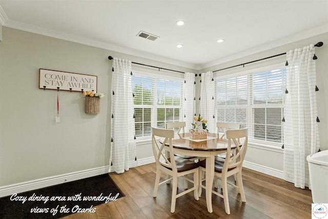 dining space featuring wood finished floors, visible vents, ornamental molding, and baseboards