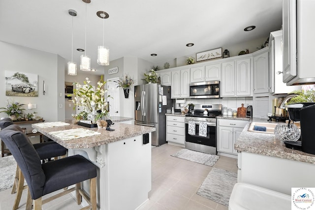 414 S Borgman Rd, Buckner, MO 64016 - kitchen featuring stainless steel appliances, a kitchen island, decorative backsplash, a kitchen bar, and light tile patterned floors