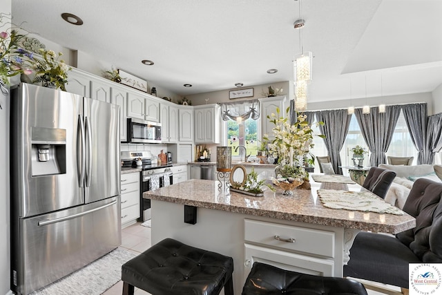 414 S Borgman Rd, Buckner, MO 64016 - kitchen featuring stainless steel appliances, a breakfast bar area, light tile patterned floors, and light stone counters