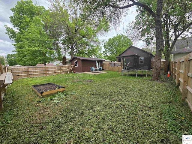 1824 S Grand Ave, Sedalia, MO 65301 - fenced backyard featuring a garden, a trampoline, and an outbuilding
