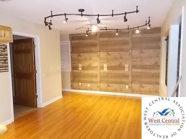 interior space with rail lighting, baseboards, and wood finished floors