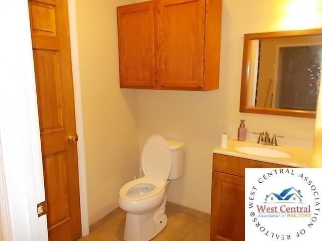 half bathroom featuring tile patterned floors, toilet, baseboards, and vanity