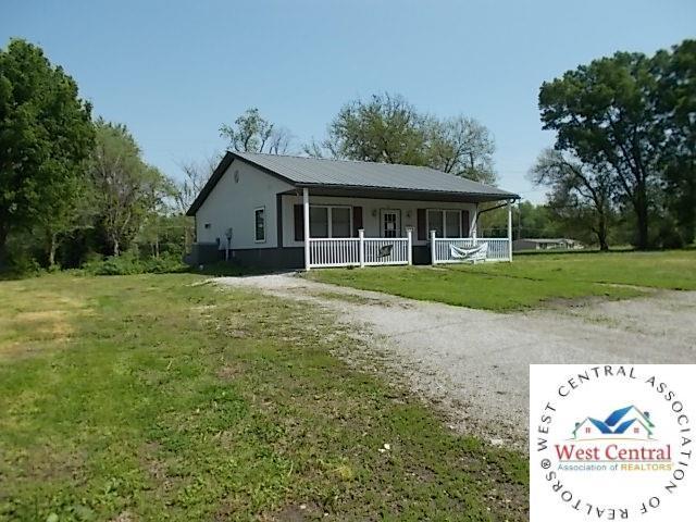view of front of property with a front lawn, metal roof, dirt driveway, and covered porch