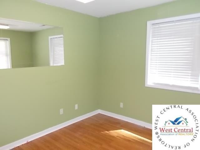 spare room with wood finished floors and baseboards