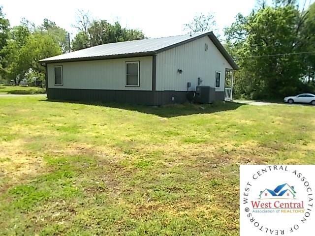 view of side of property with a yard and central AC unit