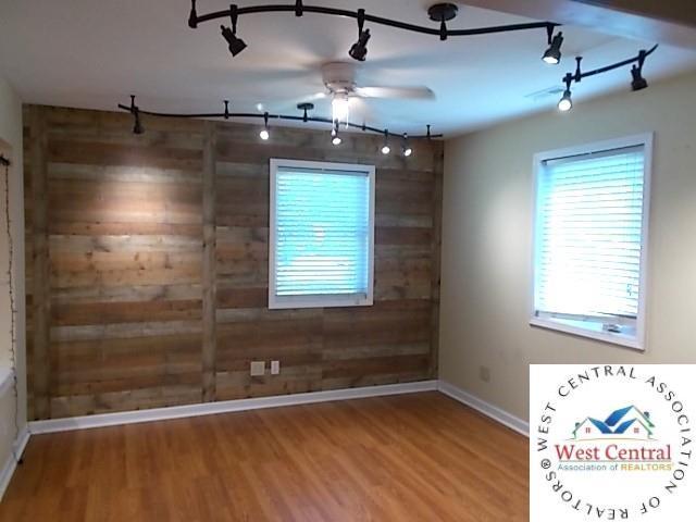 unfurnished room with baseboards, a ceiling fan, track lighting, and wood finished floors