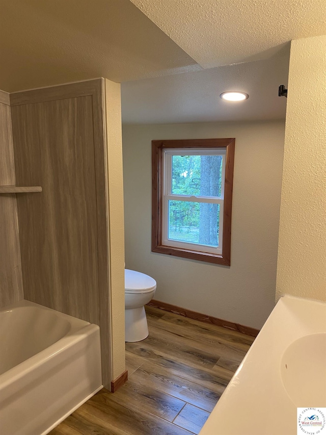 full bathroom featuring baseboards, recessed lighting, wood finished floors, and toilet