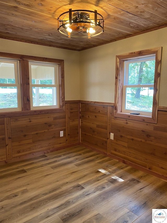 empty room featuring wainscoting, an inviting chandelier, and wooden walls