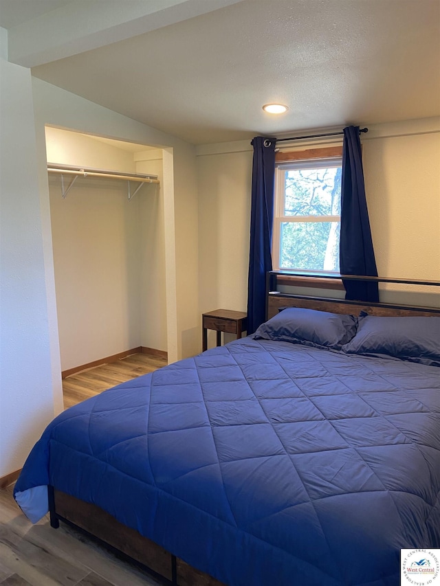 bedroom featuring wood finished floors, baseboards, and a closet