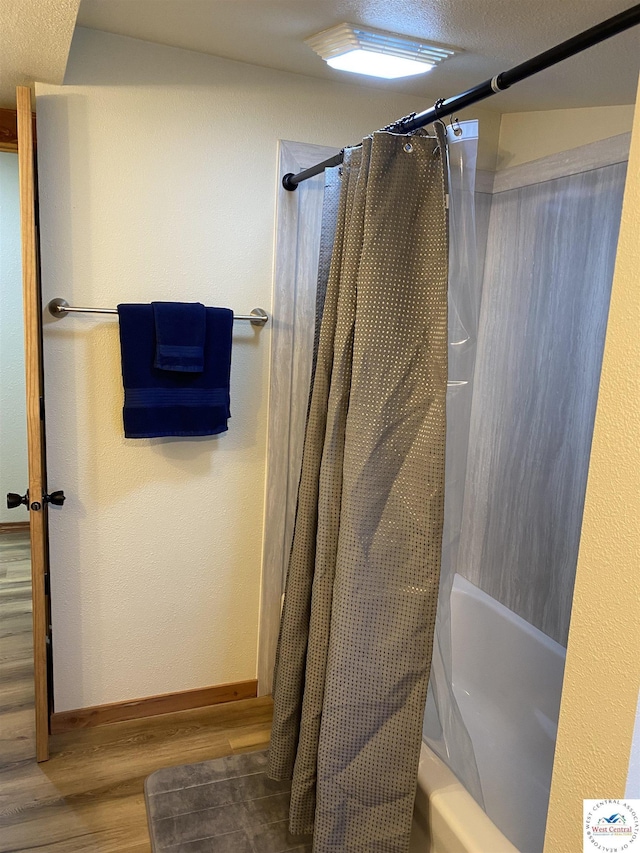 bathroom with baseboards, shower / bath combo with shower curtain, and wood finished floors