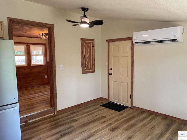 entrance foyer featuring a wall mounted AC, a ceiling fan, vaulted ceiling, baseboards, and wood finished floors