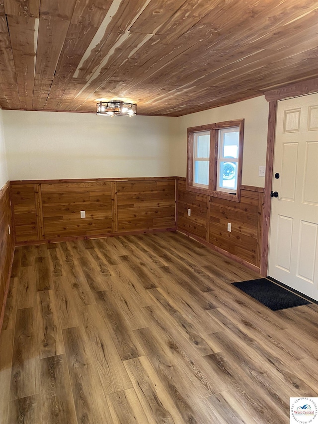 below grade area featuring a wainscoted wall, wood walls, wood finished floors, and wood ceiling