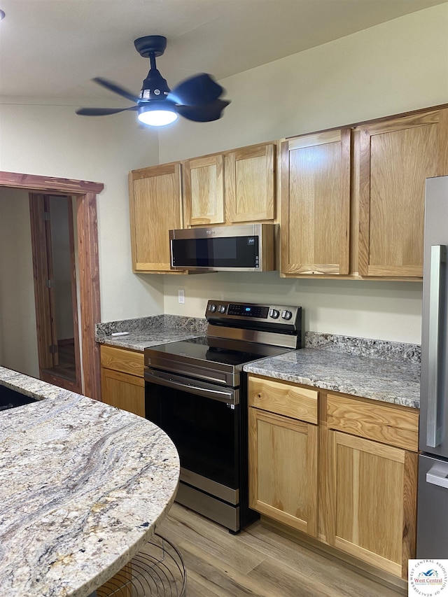 kitchen with light brown cabinets, a ceiling fan, appliances with stainless steel finishes, and light wood-style flooring