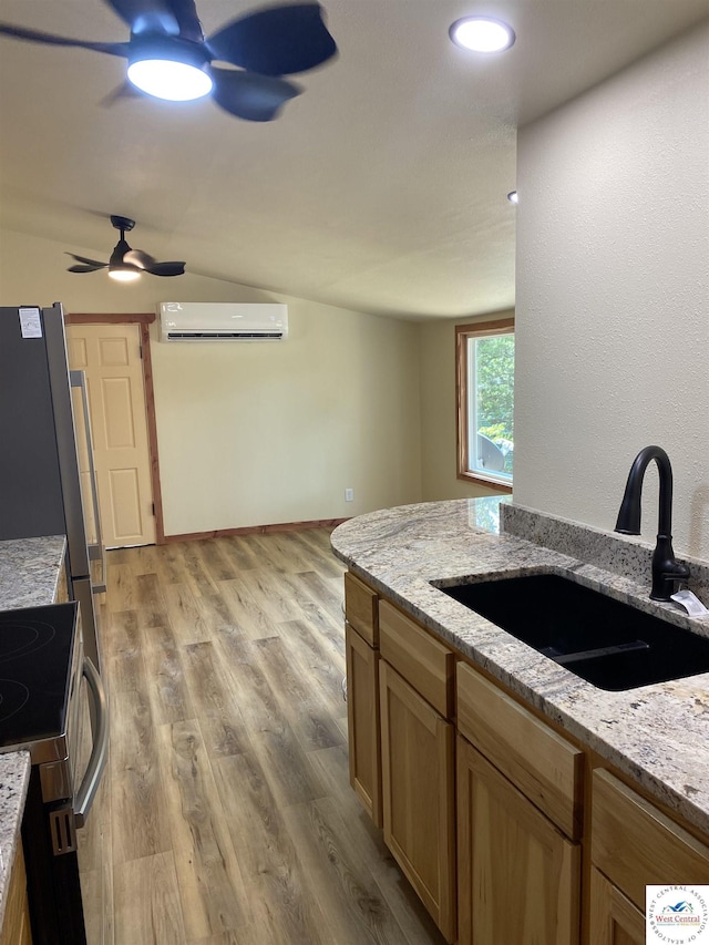 kitchen featuring light stone counters, ceiling fan, light wood-type flooring, and a sink