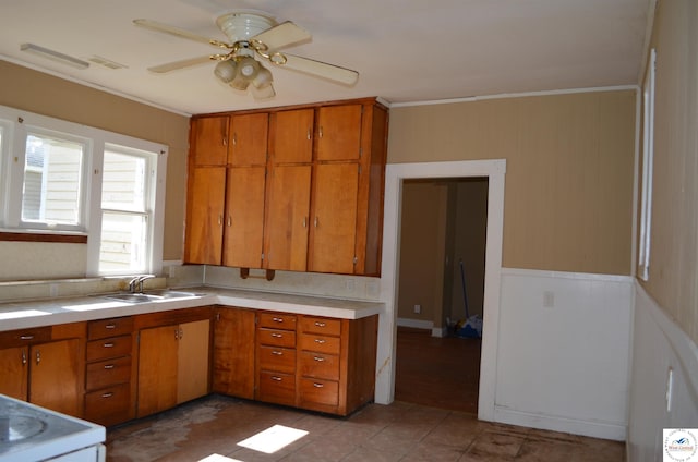 1305 E 14th St, Sedalia, MO 65301 - kitchen featuring brown cabinets, ornamental molding, light countertops, ceiling fan, and a sink