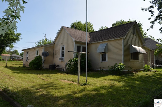 1305 E 14th St, Sedalia, MO 65301 - view of side of property featuring a lawn, roof with shingles, and central AC unit