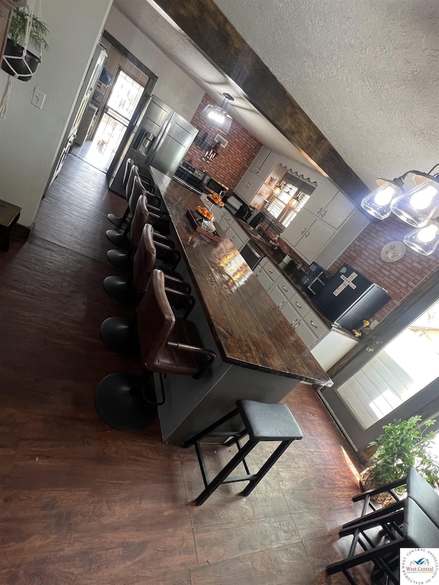 kitchen with wood finished floors, a textured ceiling, and a kitchen bar