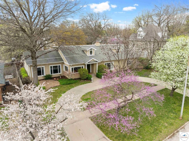 new england style home with a front lawn, a shingled roof, and a chimney