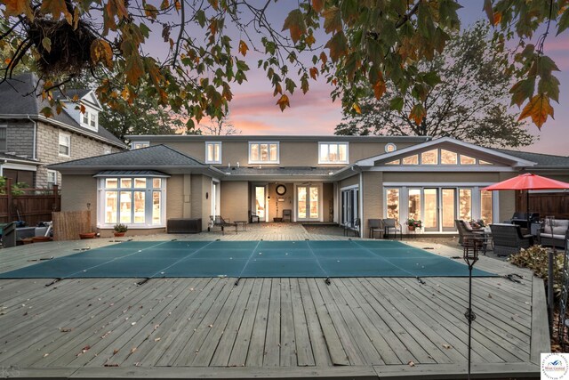 1114 W Broadway Blvd, Sedalia, MO 65301 - back of property at dusk with a deck, an outdoor living space, a fenced in pool, and fence