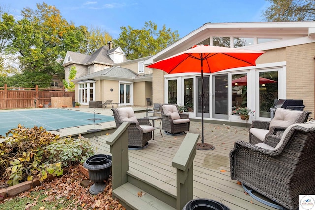 exterior space featuring a fenced in pool, a deck, fence, french doors, and brick siding