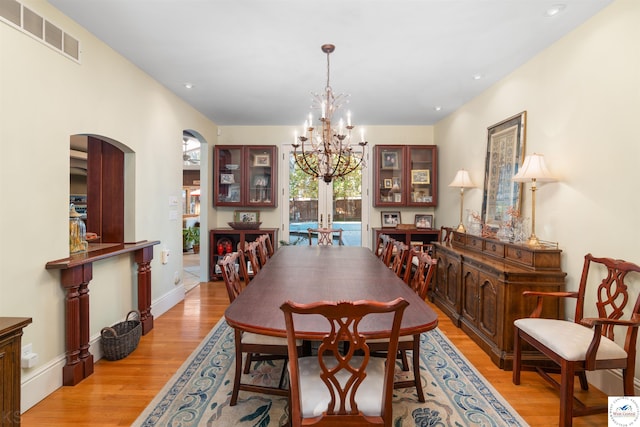 dining room featuring visible vents, light wood-style floors, arched walkways, an inviting chandelier, and recessed lighting