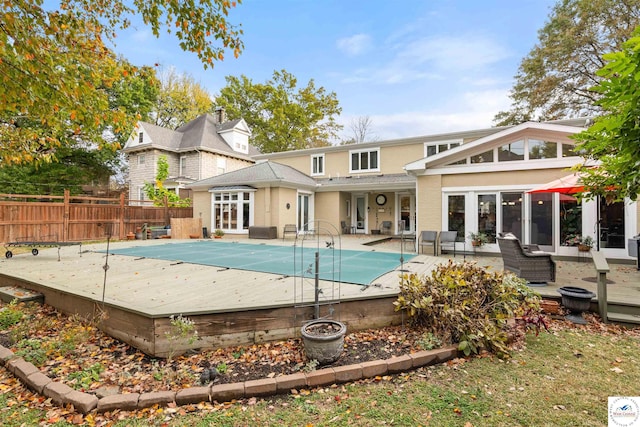rear view of property with fence, an outdoor living space, a wooden deck, and a fenced in pool