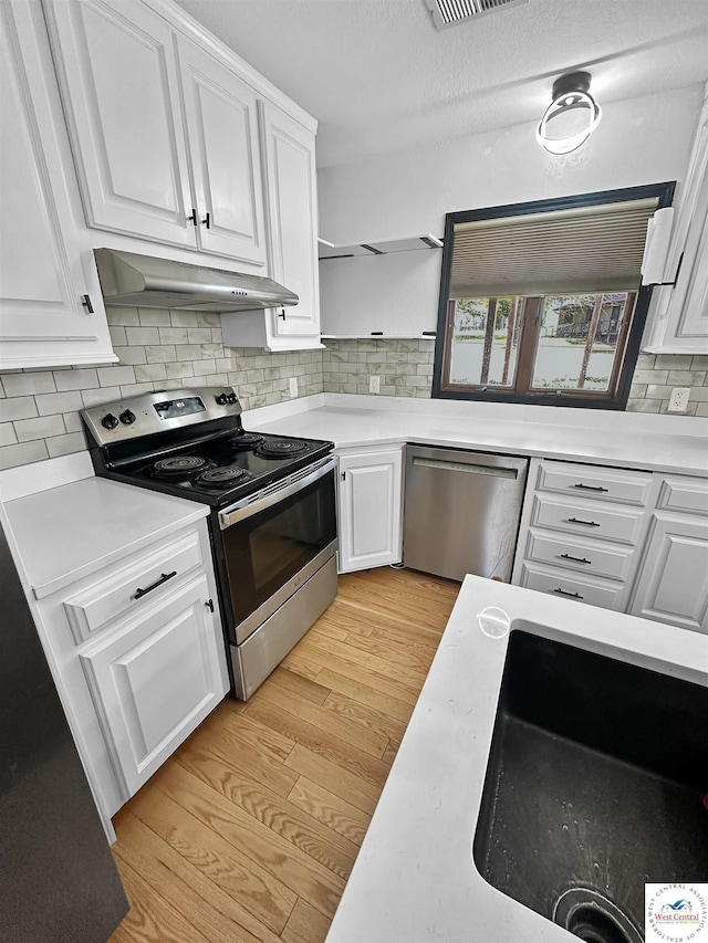 29125 Westwood Ave, Warsaw, MO 65355 - kitchen with light countertops, appliances with stainless steel finishes, under cabinet range hood, and white cabinetry