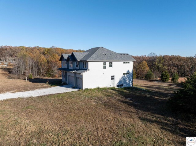 19166 Brockman Ave, Cole Camp, MO 65325 - view of side of property featuring an attached garage, a yard, and gravel driveway