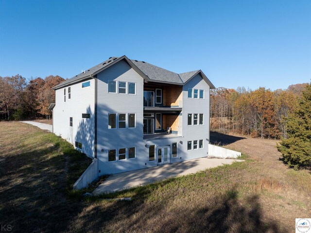 19166 Brockman Ave, Cole Camp, MO 65325 - back of property with a balcony, a patio area, a wooded view, and a yard