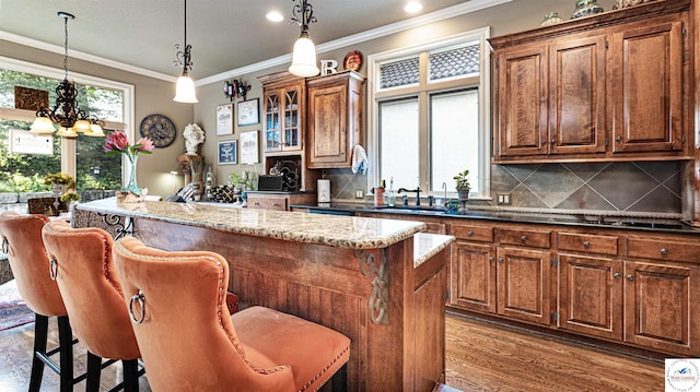4517 NE Fairway Homes Dr, Lees Summit, MO 64064 - kitchen featuring a breakfast bar area, a kitchen island, backsplash, wood finished floors, and ornamental molding