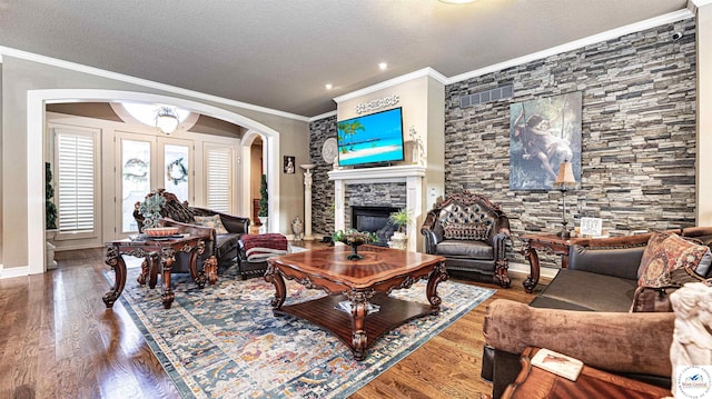 4517 NE Fairway Homes Dr, Lees Summit, MO 64064 - living room with arched walkways, a stone fireplace, wood finished floors, ornamental molding, and a textured ceiling
