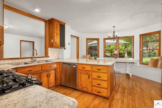 2105 Stonewood Cir, Sedalia, MO 65301 - kitchen with stainless steel dishwasher, a peninsula, light wood-style floors, brown cabinets, and a textured ceiling