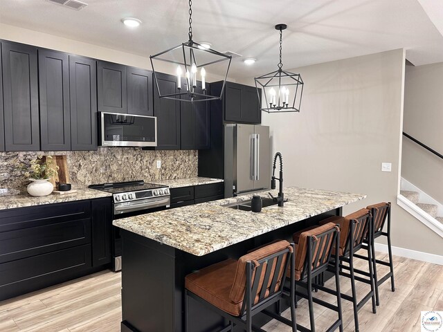 28927 Benton House Ave, Warsaw, MO 65355 - kitchen with tasteful backsplash, appliances with stainless steel finishes, dark cabinets, and light wood-style floors