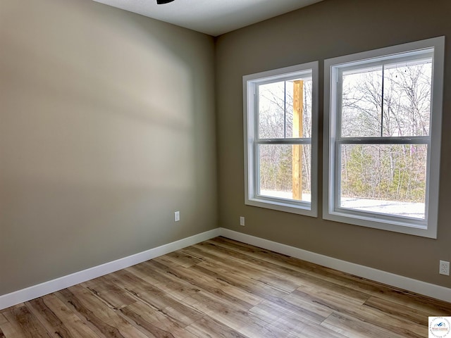 spare room with a ceiling fan, wood finished floors, and baseboards