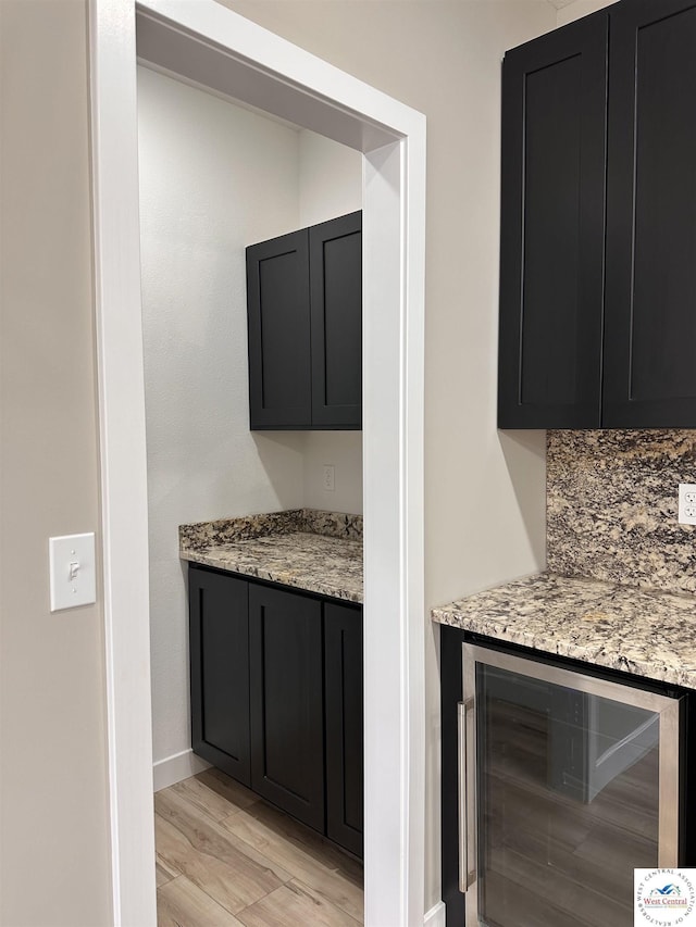 bar featuring wine cooler, baseboards, and light wood-style floors