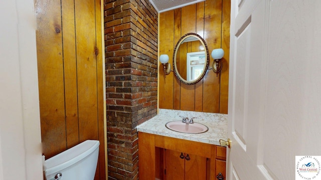 401 N Prospect St, Sedalia, MO 65301 - half bath featuring wooden walls, toilet, vanity, and brick wall